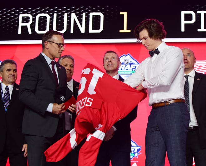 Detroit Red Wings GM Steve Yzerman watches, as Moritz Seider puts on a jersey after being selected sixth overall in the first round of the NHL draft at Rogers Arena, June 21, 2019 in Vancouver.
