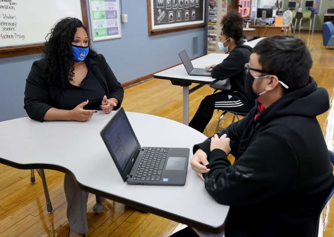 Marti Diaz, who teaches financial literacy at Milwaukee Public Schools, works with personal finance students, Edison Lee, right, and Mariah Jones, center, who are both seniors at Riverside High School.